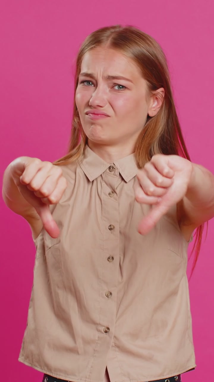 Upset attractive young woman lady showing thumbs down sign gesture disapproval dissatisfied dislike