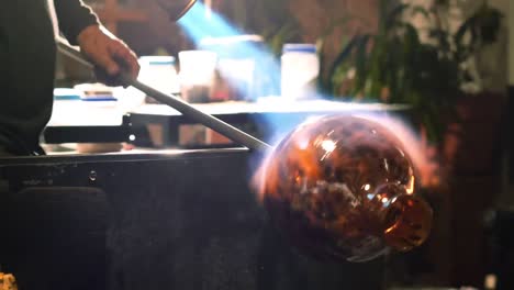 Glassblower-blowing-propane-gas-flame-on-finished-piece-of-glass