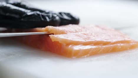 cook cuts red fish with a knife