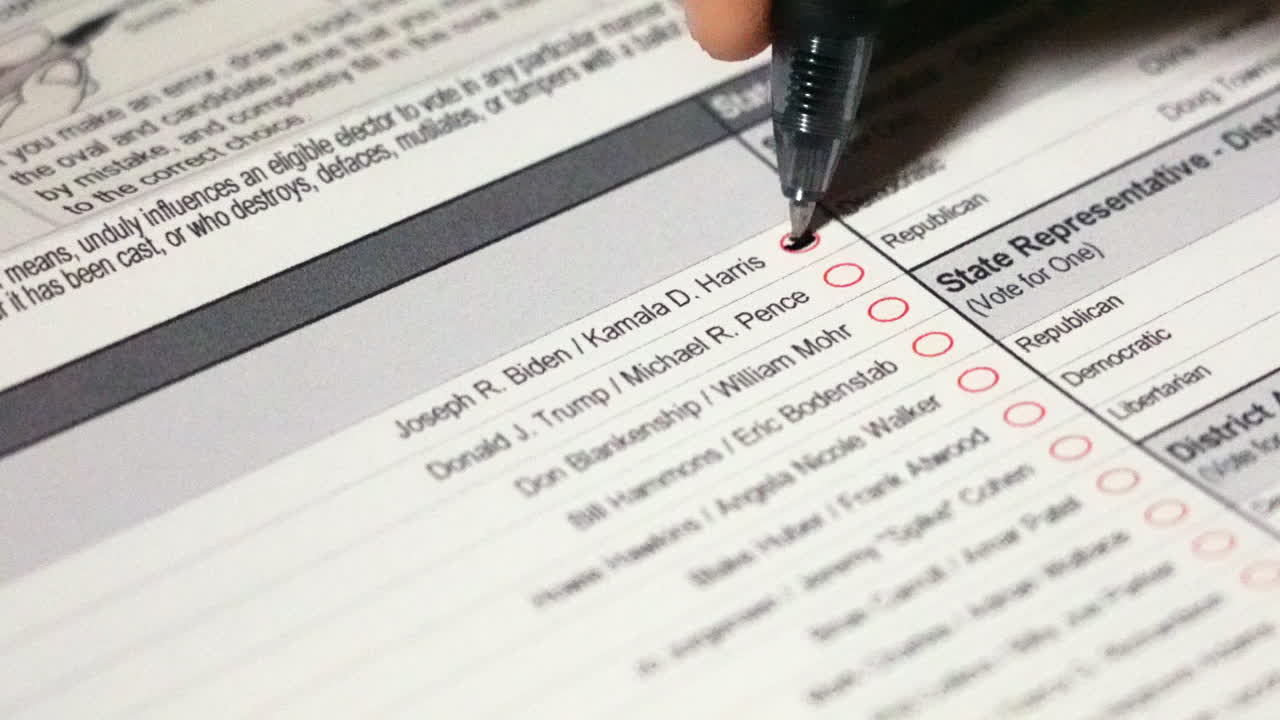 votando por joe biden y kamela harris llenando una burbuja con un bolígrafo en la boleta de las elecciones presidenciales de 2020 de cerca
