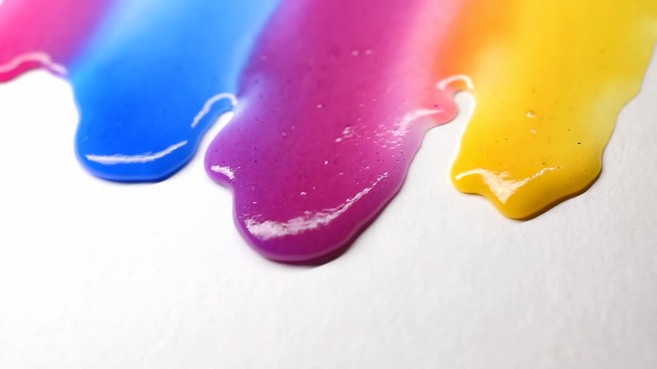 Líquido vibrante y colorido goteando y extendiéndose sobre superficie blanca