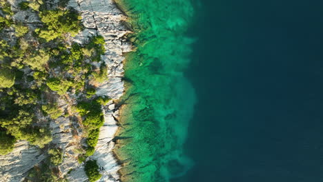 Top-down-drone-dolley-shot-of-the-clear-Adriatic-sea-next-of-the-Croatian-shore