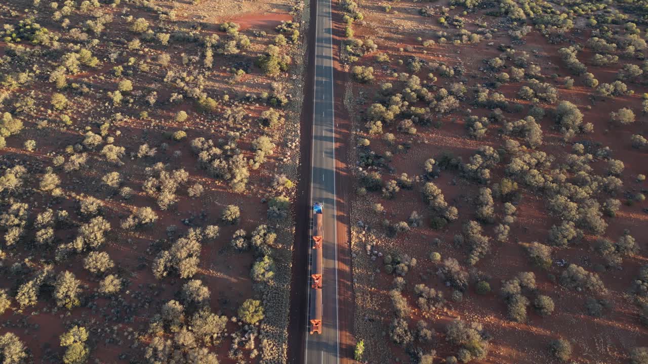 camión de carga conduciendo por una carretera rural en el desierto australiano al atardecer, australia occidental