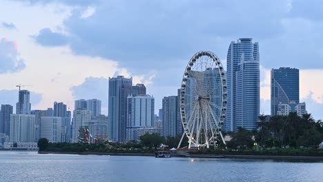 Dec-2020:-The-iconic-Eye-of-the-Emirates-wheel-of-Sharjah,-Sharjah-Skyline-in-the-background-on-a-cloudy-evening,-United-Arab-Emirates,-4K-video