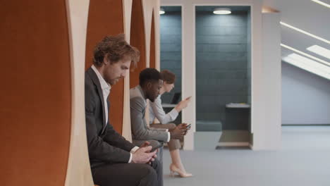 three businesspeople using smartphones in office