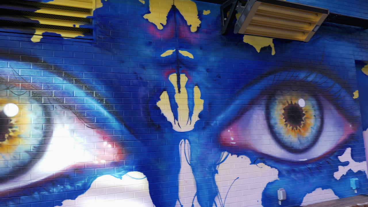 Panning view of large eyes, painted on a brick wall, by a street artist in Downtown Denver Colorado