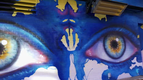 panning view of large eyes, painted on a brick wall, by a street artist in downtown denver colorado