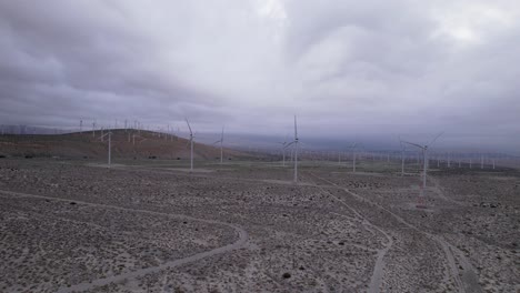 Aerial-footage-of-a-wind-farm-in-the-Palm-Springs-desert-on-a-cloudy-day,-wide-dolly-forward-shot