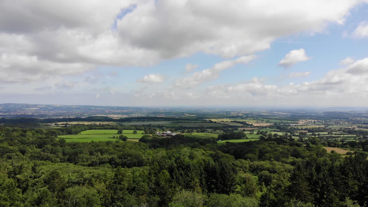 A picturesque aerial view showcasing the Blackdown Hills National Landscape, featuring lush greenery and expansive rural scenery under a sky of light clouds.