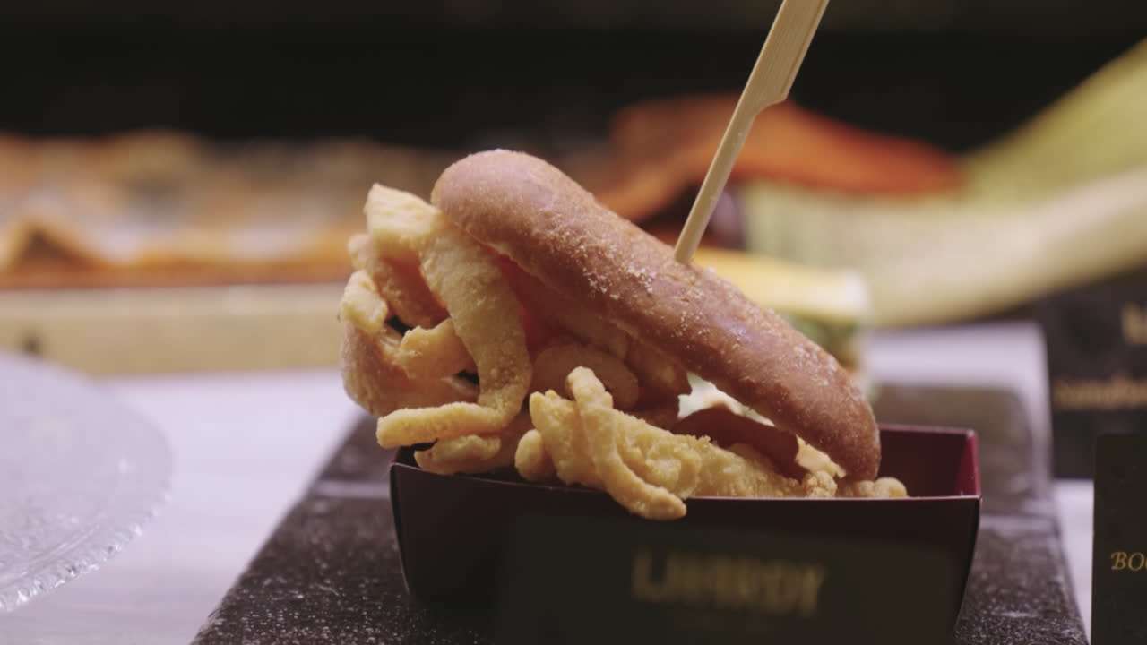 Beautiful close-up shot of a breaded chicken burger on a table in a Madrid restaurant in daylight.