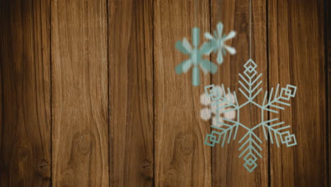 Animación-De-Adornos-Navideños-De-Copos-De-Nieve-Sobre-Fondo-De-Madera.