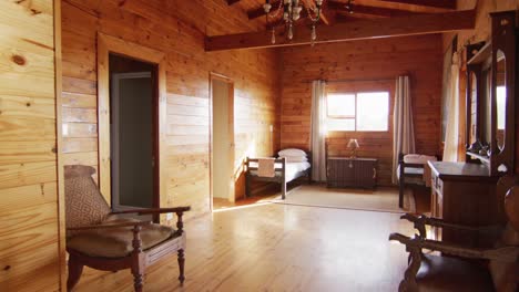 general view of bedroom with beds and armchairs in log cabin, slow motion