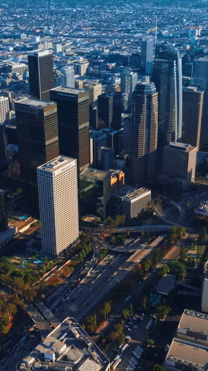 Majestic skyscrapers towering over the financial downtown. Lively traffic through the city center of Los Angeles at daytime. Top view. Vertical video