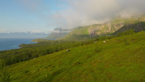 a view of green mountains and foggy sky during summer in lofoten islands, norway