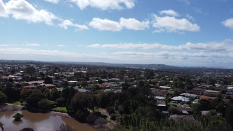 4k video of drone ascending from a green garden with a lake showing a residential suburb in toowoomba, australia
