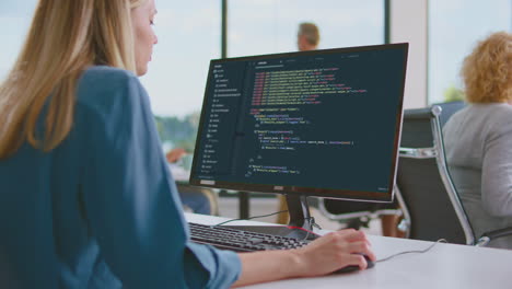 woman programmer coding on computer in office