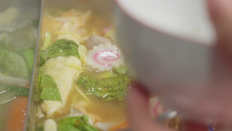 serving shabu shabu soup with kagosei narutomaki, fish balls, vegetables and enoki mushroom