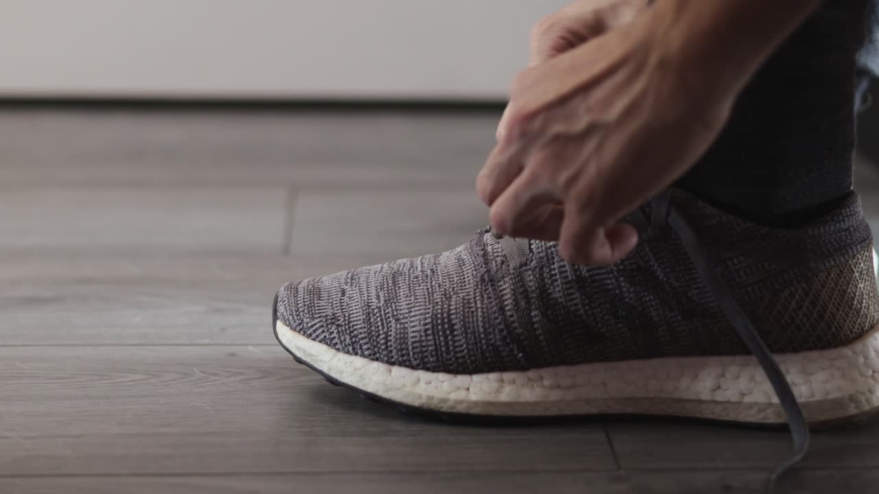 Vista laterale sinistra delle scarpe da corsa di un uomo che si allaccia i lacci prima di andare a correre
