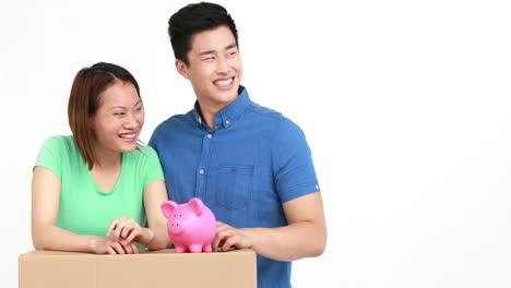 cute couple with moving box and piggy bank