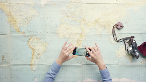 Top-view-woman-traveler-photographing-locations-on-vintage-world-map-desk-from-above---Red-Epic-Dragon