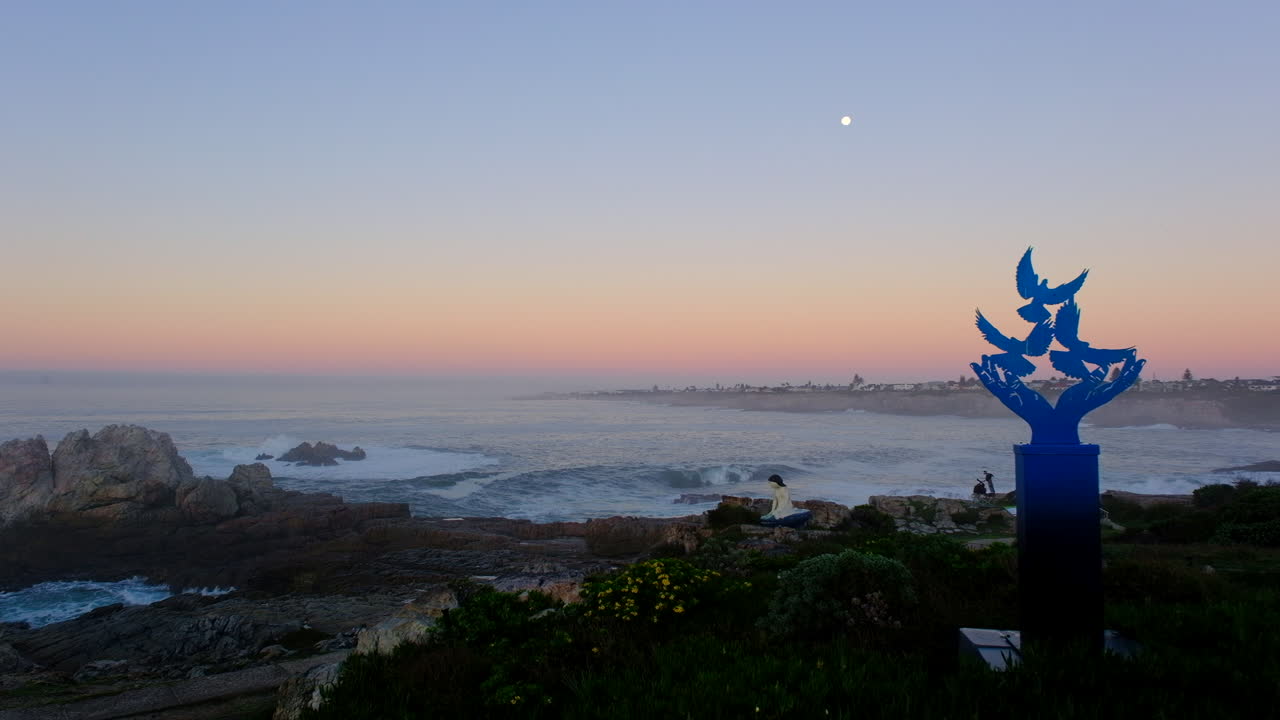 View of full moonset at blue hour from Hermanus coastline with artwork
