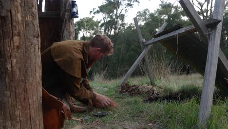 australian bush man starting fire with a flint and steel in a historical bark hut