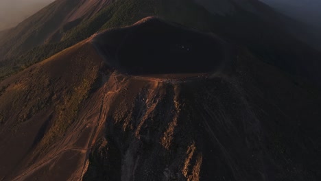 Vista-Aérea-Inclinada-Sobre-Los-Turistas-En-Una-Caldera-Vacía-Frente-A-Un-Volcán-Humeante