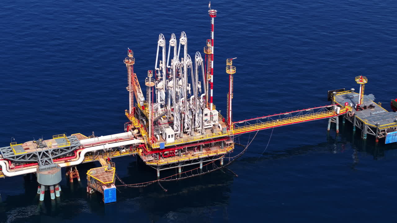 Drone shot moving away from offshore oil structure, showing refinery equipment and platforms in Sicily