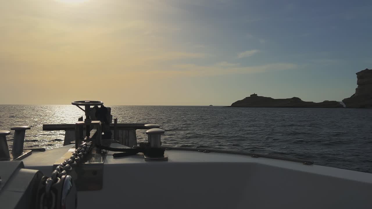 perspectiva desde la proa del barco de vela con sol brillante en frente y acantilados de la isla de córcega y faro de capo pertusato en el fondo, francia-2