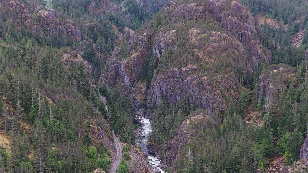 River Flows Through a Lush Valley With Mountain Peaks and a Rail Line in BC