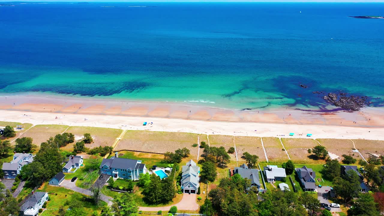 Aerial drone view of a stunning Maine cottage. Sandy yard, big windows, deck, and ocean views create a perfect beach house for relaxing family holidays and prime real estate by the sea