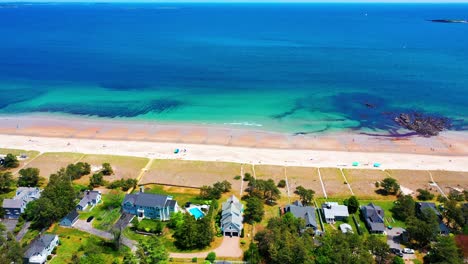 aerial drone view of a stunning maine cottage. sandy yard, big windows, deck, and ocean views create a perfect beach house for relaxing family holidays and prime real estate by the sea