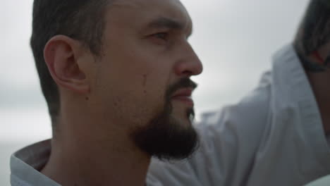 closeup man face practicing karate on beach. sporty man making fighting exercise