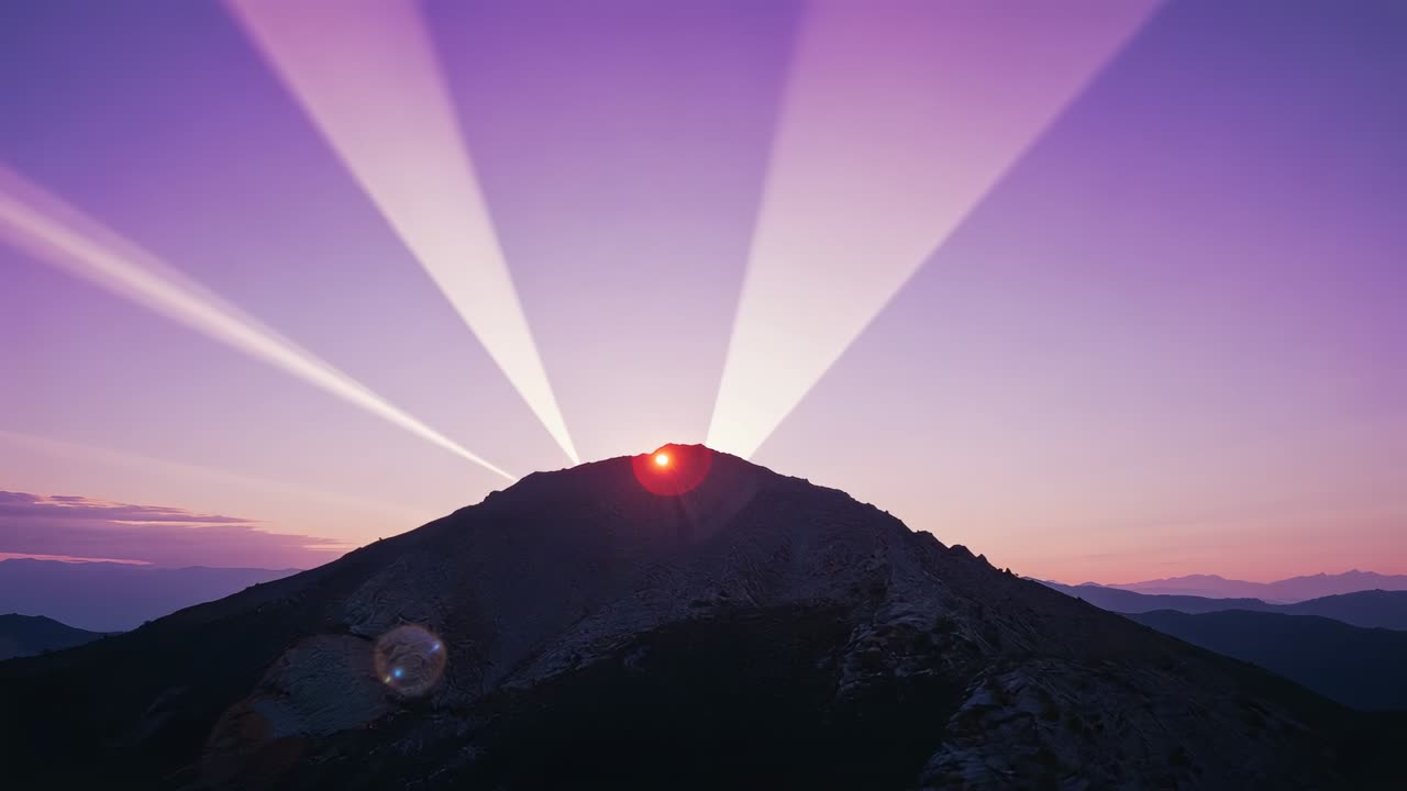 Rising sun cresting mountain ridge at sunrise, casting beams, lighting pink sky and lens flare