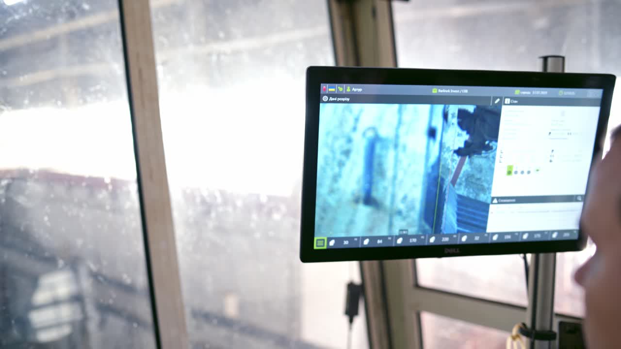 Robotic power-saw bench indoors. Worker looking on the monitor where automated machine cutting wood. Modernized equipment inside the woodworking plant.