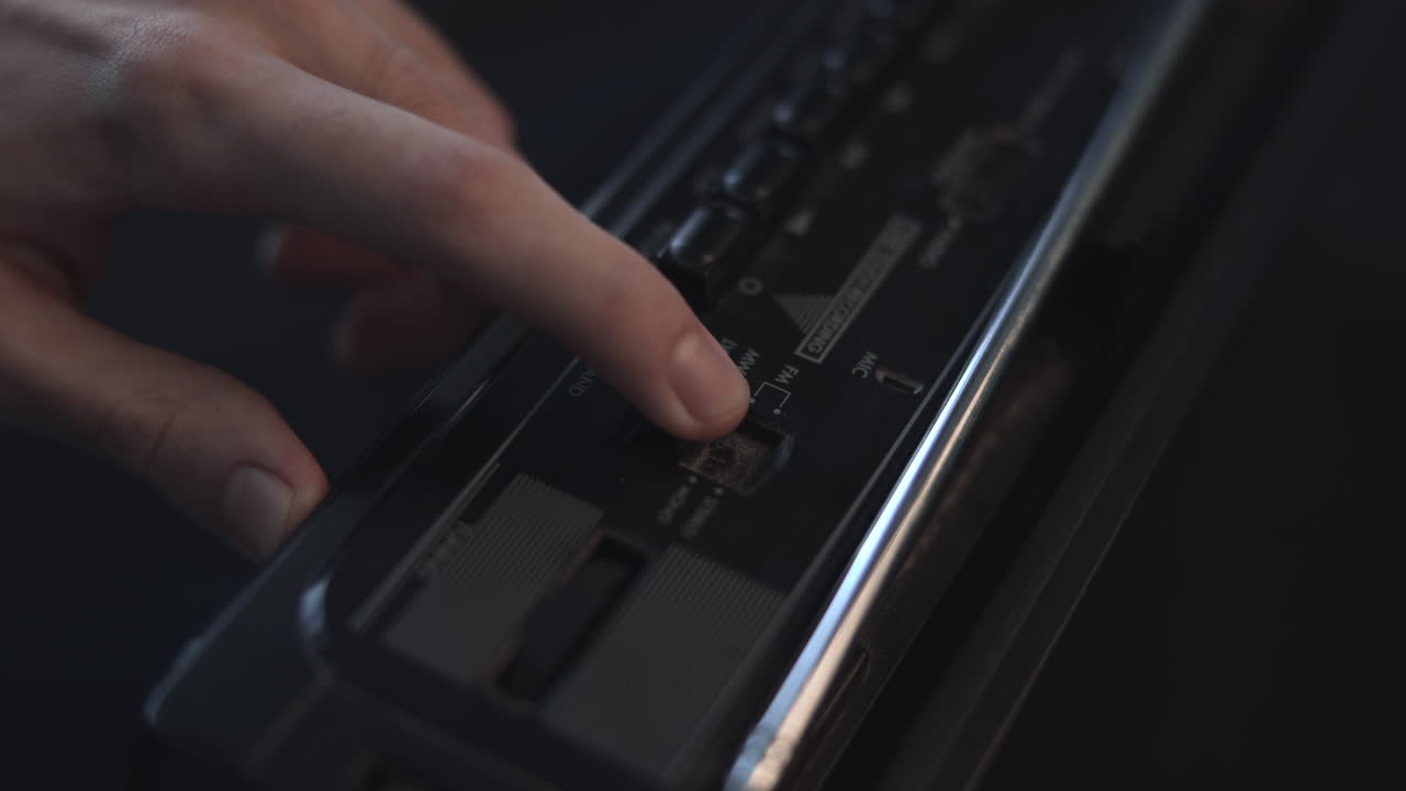 Closeup Vintage Radio Control Panel Showing Finger Pressing Tactile Button, Dim Studio Lighting, Metallic