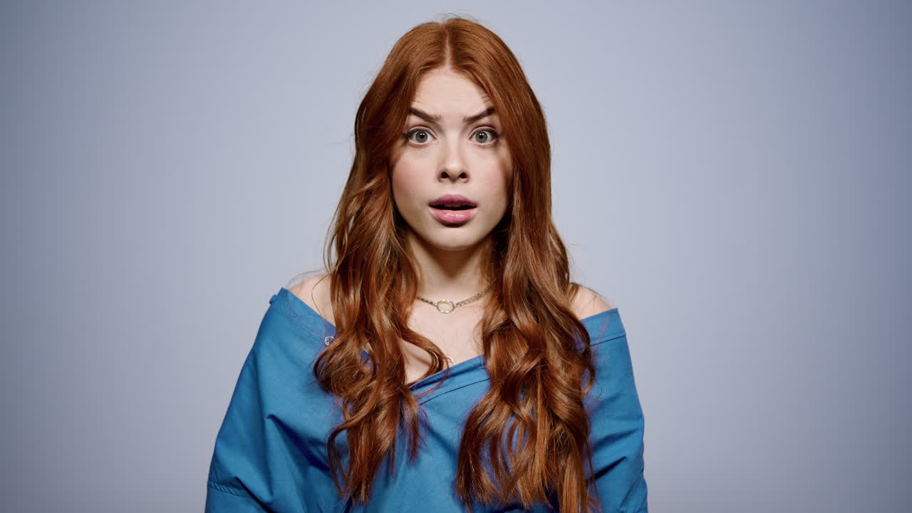 스튜디오에서 카메라를 바라보는 좌절한 소녀. 실내에서 포즈를 취하는 충격적인 여성