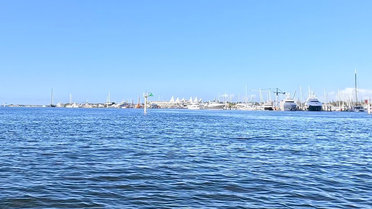 A serene view of calm waters with a distant marina and clear blue skies.