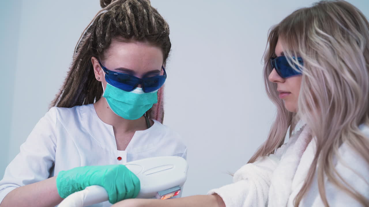 mujer con rastas hace depilación con láser a una chica en el salón