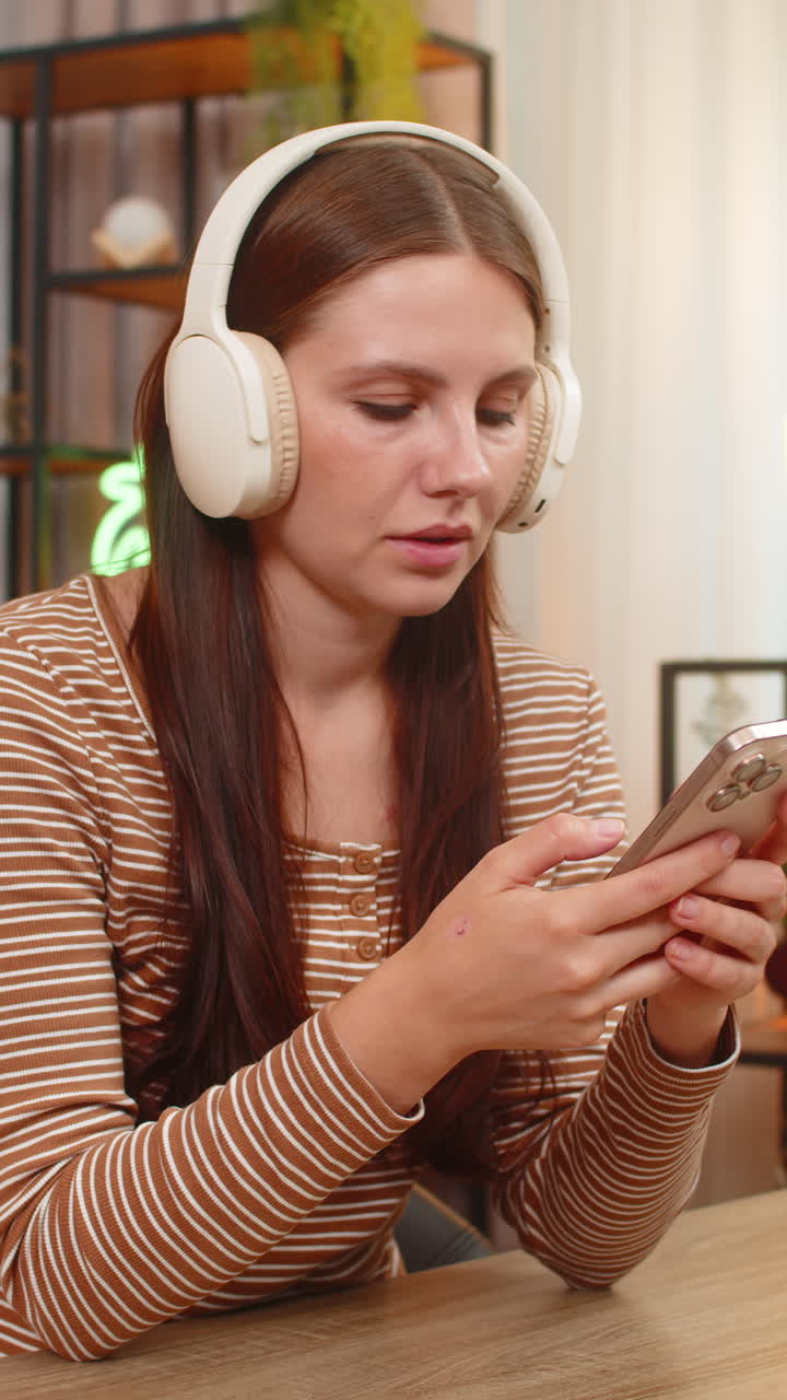 Giovane donna con cuffie ascolta un podcast sulla produttività e annota idee sullo smartphone per le attività.
