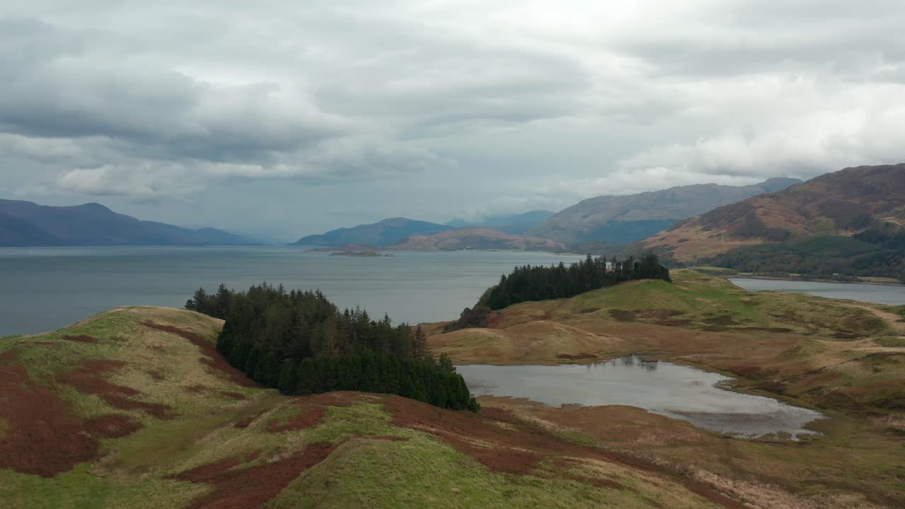 Aerial drone panoramic fly over shot. Forwarding view. Beautiful Scotland highlands. Remote rural area, fall colors, fields, forests with sea and mountain range in the background. 4k footage.