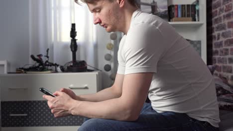 a serious young man enters the room and sits on the bed gently