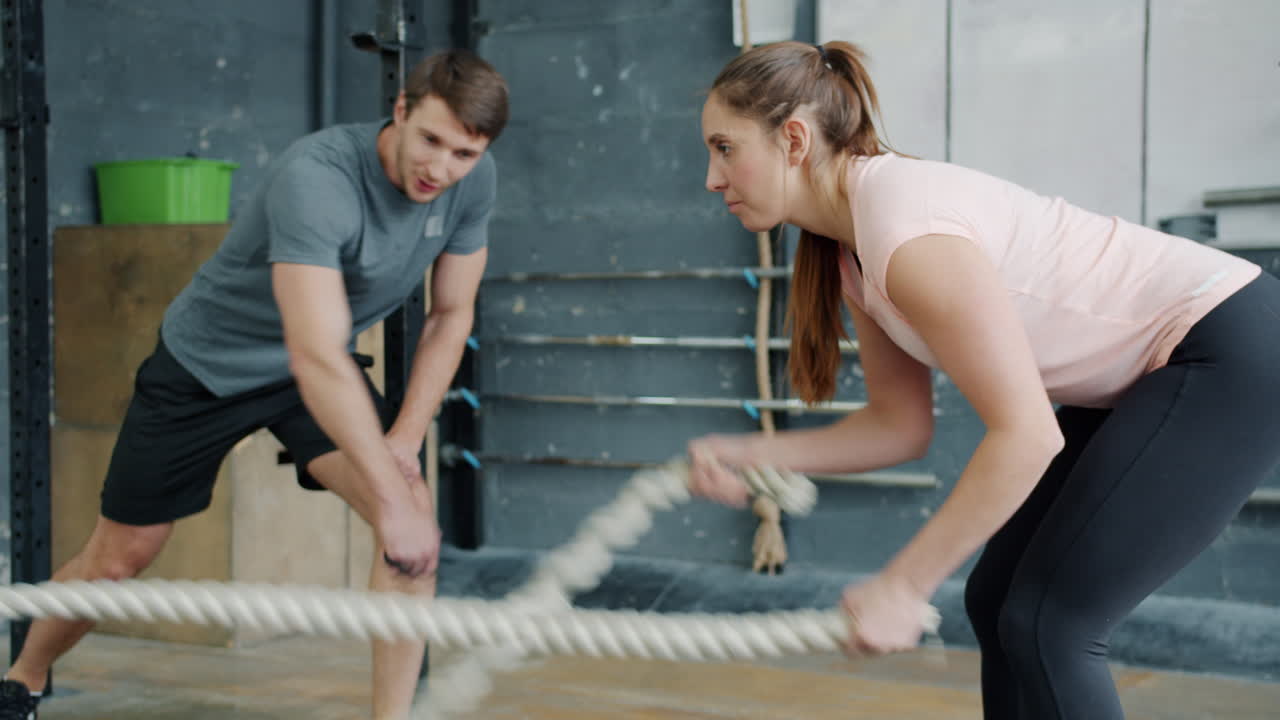 Couple working out with ropes in gym