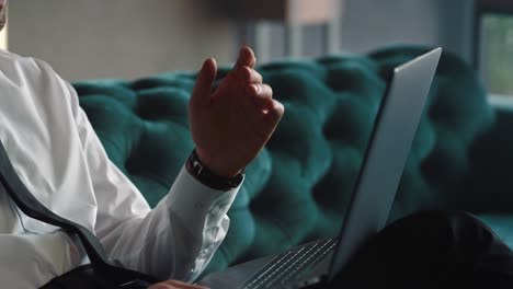 hombre de negocios irreconocible agitando la mano en la cámara de la computadora portátil en un lugar de trabajo remoto