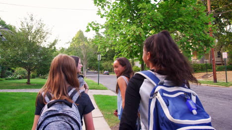 Four-girls-walk-to-school-together,-back-view-tracking-shot