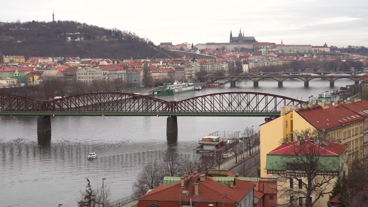 Blick über die Moldau in Prag, mit Burg in der Ferne an einem grauen und bewölkten Wintertag.
