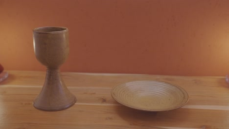 brown porcelain chalice and paten - sacred ornaments on the wooden altar for catholic mass - dolly shot