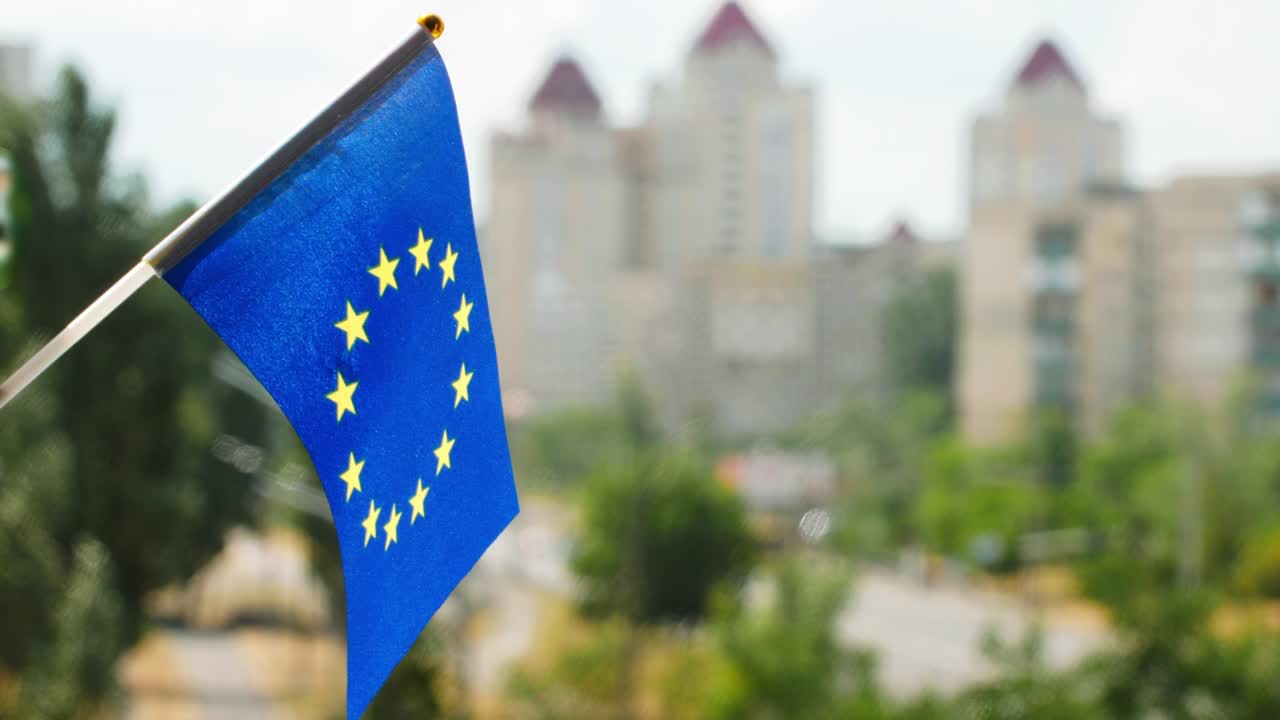 bandera de la unión europea puesta contra el cielo azul y la calle de la ciudad. bandera de europa ondeando. círculo de estrellas doradas en la bandera europea azul. la bandera de vacaciones de la ue en el sol. copiar espacio para el texto