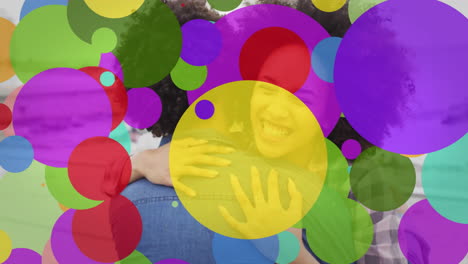 animation of colourful spots over happy biracial couple embracing on beach