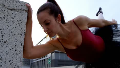 bailarina de ballet estirándose en el pavimento 4k